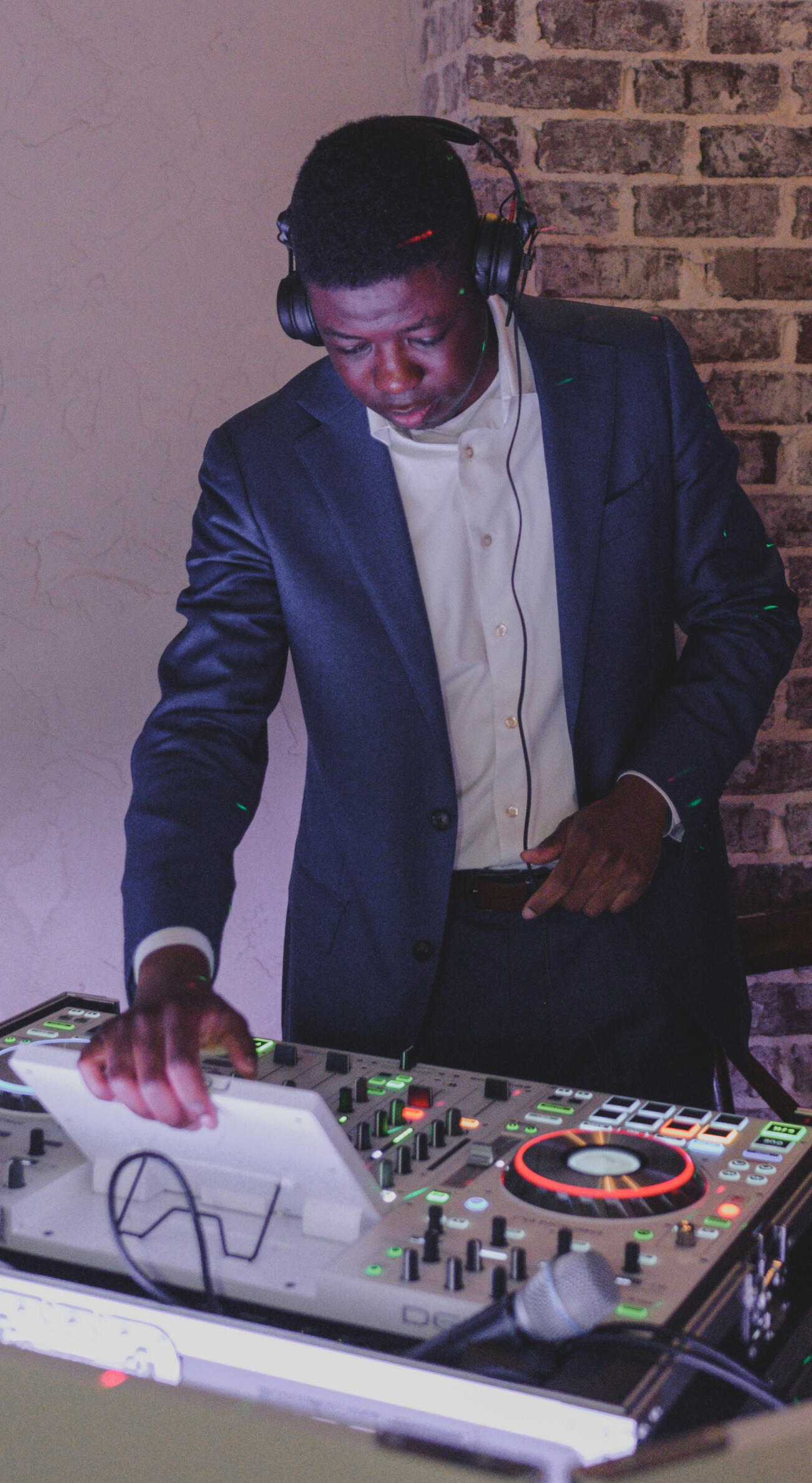 Bells Entertainment Owner A DJ in a suit wearing headphones and mixing music on his DJ controller