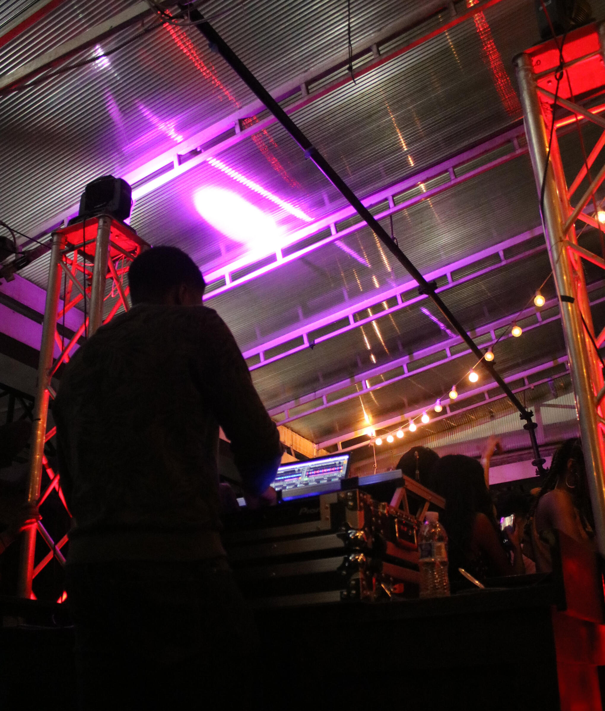 Event DJ Setup A DJ mixing music on his DJ controller, he is surrounded by vibrant lights and a crowd